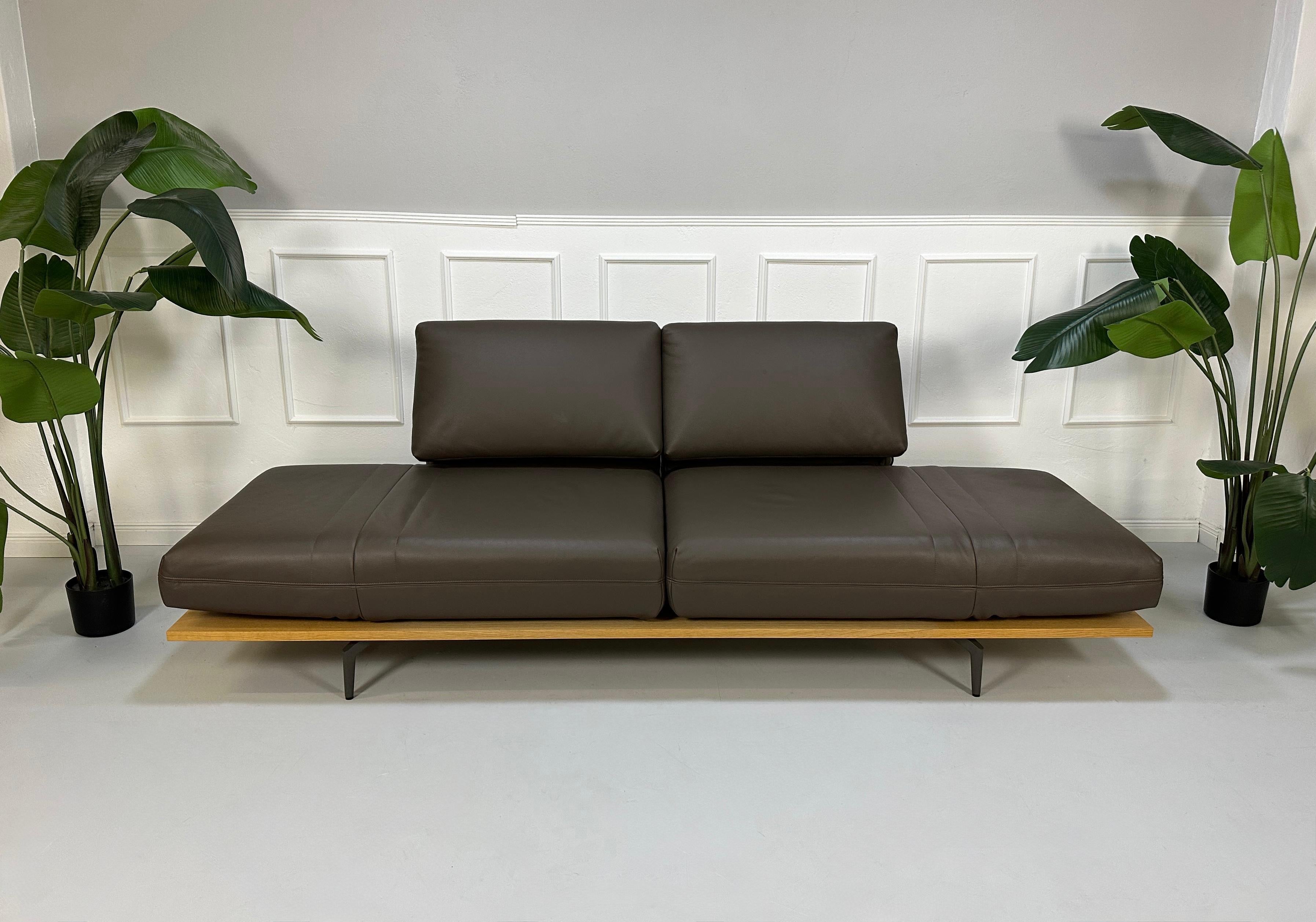 Gebrauchtes braunes Rolf Benz Aura Designer Leder Sofa vor einer Wand, stilvoll und modern eingerichtet.
