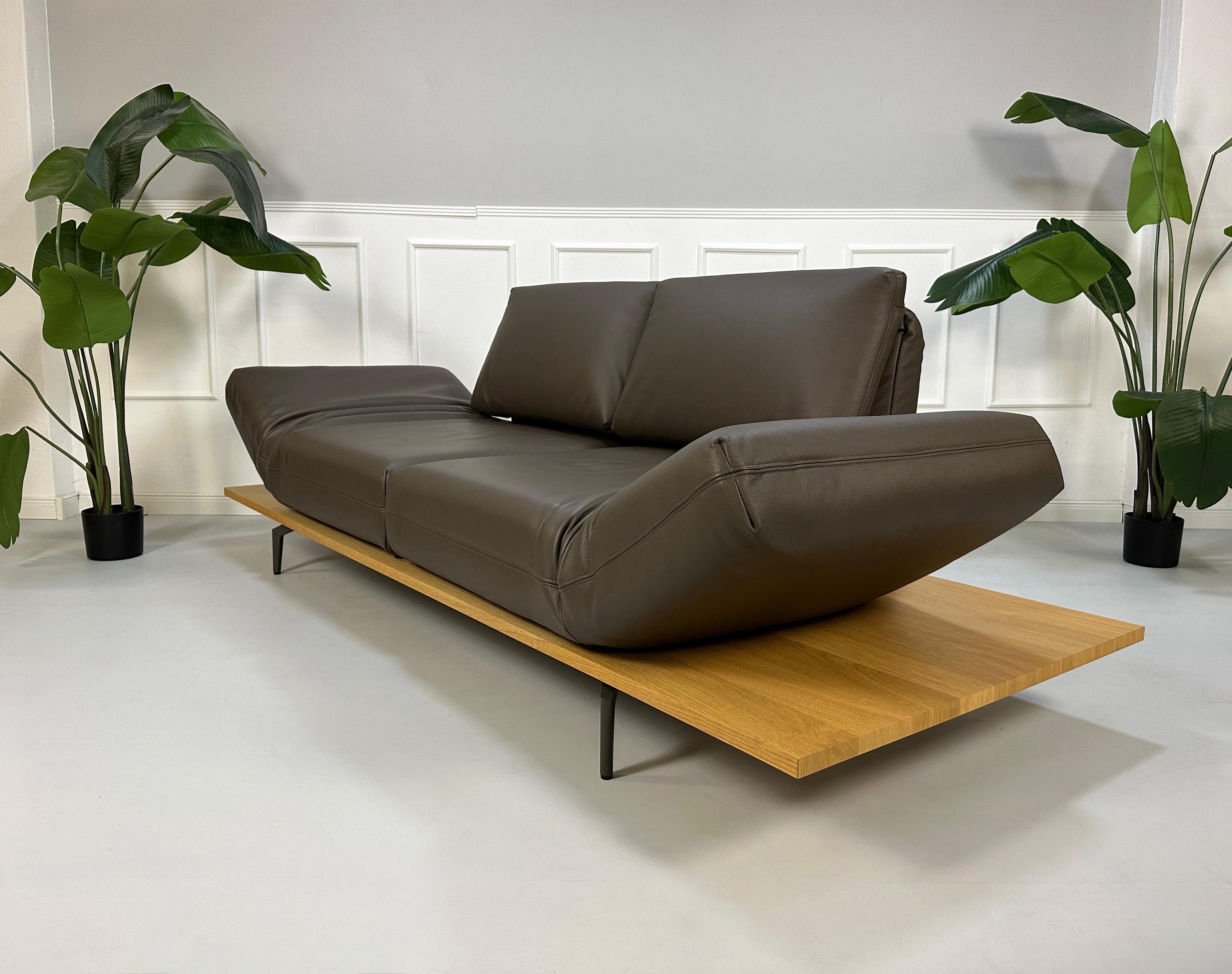 Gebrauchtes braunes Rolf Benz Aura Designer Leder Sofa vor einer Wand, stilvoll und modern eingerichtet.