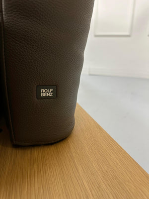 Gebrauchtes braunes Rolf Benz Aura Designer Leder Sofa vor einer Wand, stilvoll und modern eingerichtet.