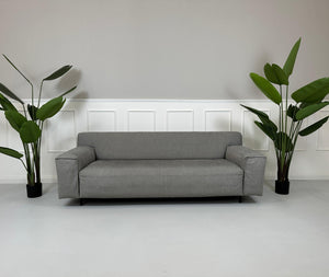 Gebrauchtes graues Rolf Benz Grata Designer Stoff Sofa vor einer Wand, stilvoll und modern eingerichtet.