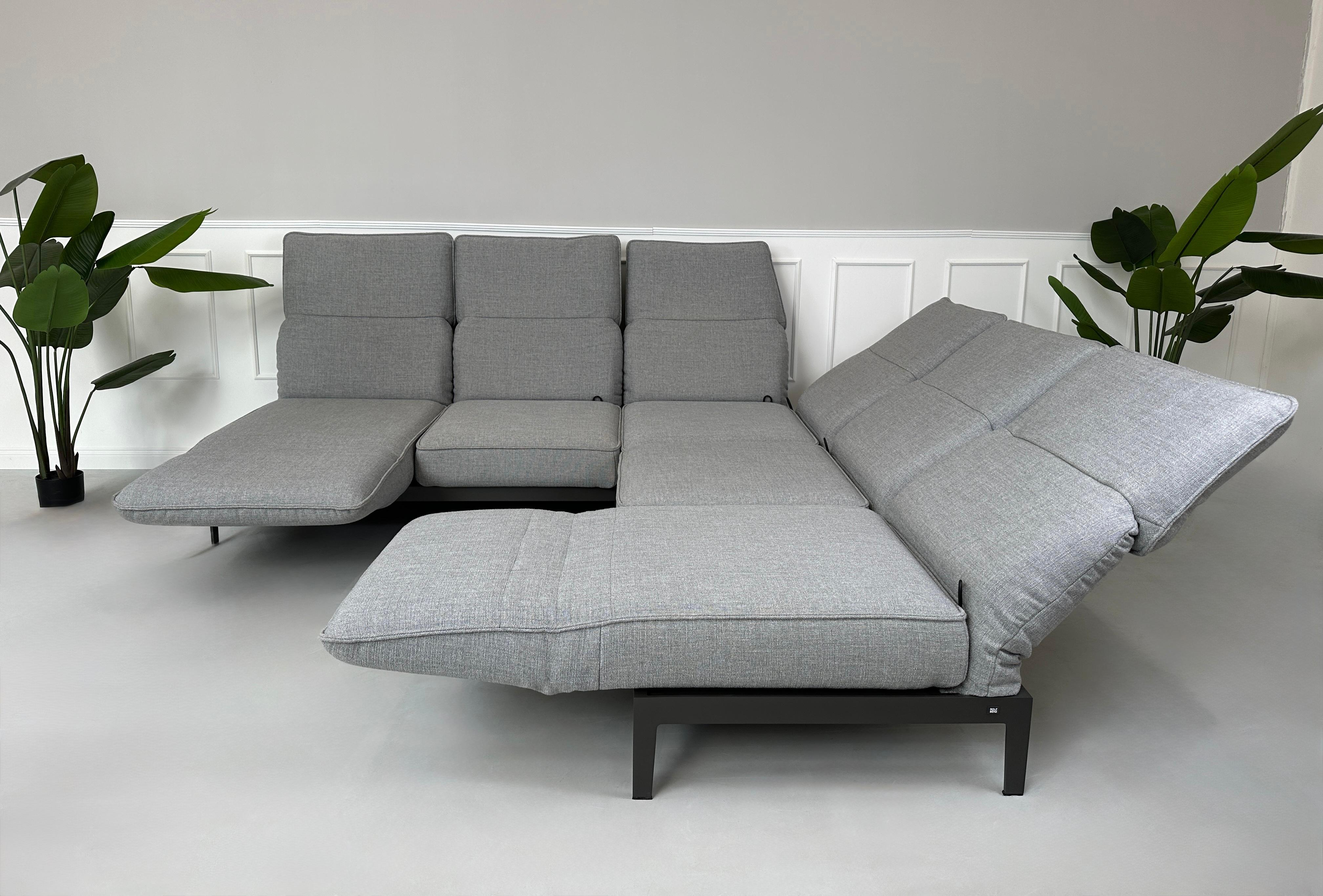 Graues Ausstellungsstück Rolf Benz Mera Designer Stoff Sofa vor einer Wand, stilvoll und modern eingerichtet.