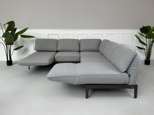 Graues Ausstellungsstück Rolf Benz Mera Designer Stoff Sofa vor einer Wand, stilvoll und modern eingerichtet.