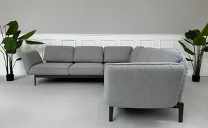 Graues Ausstellungsstück Rolf Benz Mera Designer Stoff Sofa vor einer Wand, stilvoll und modern eingerichtet.