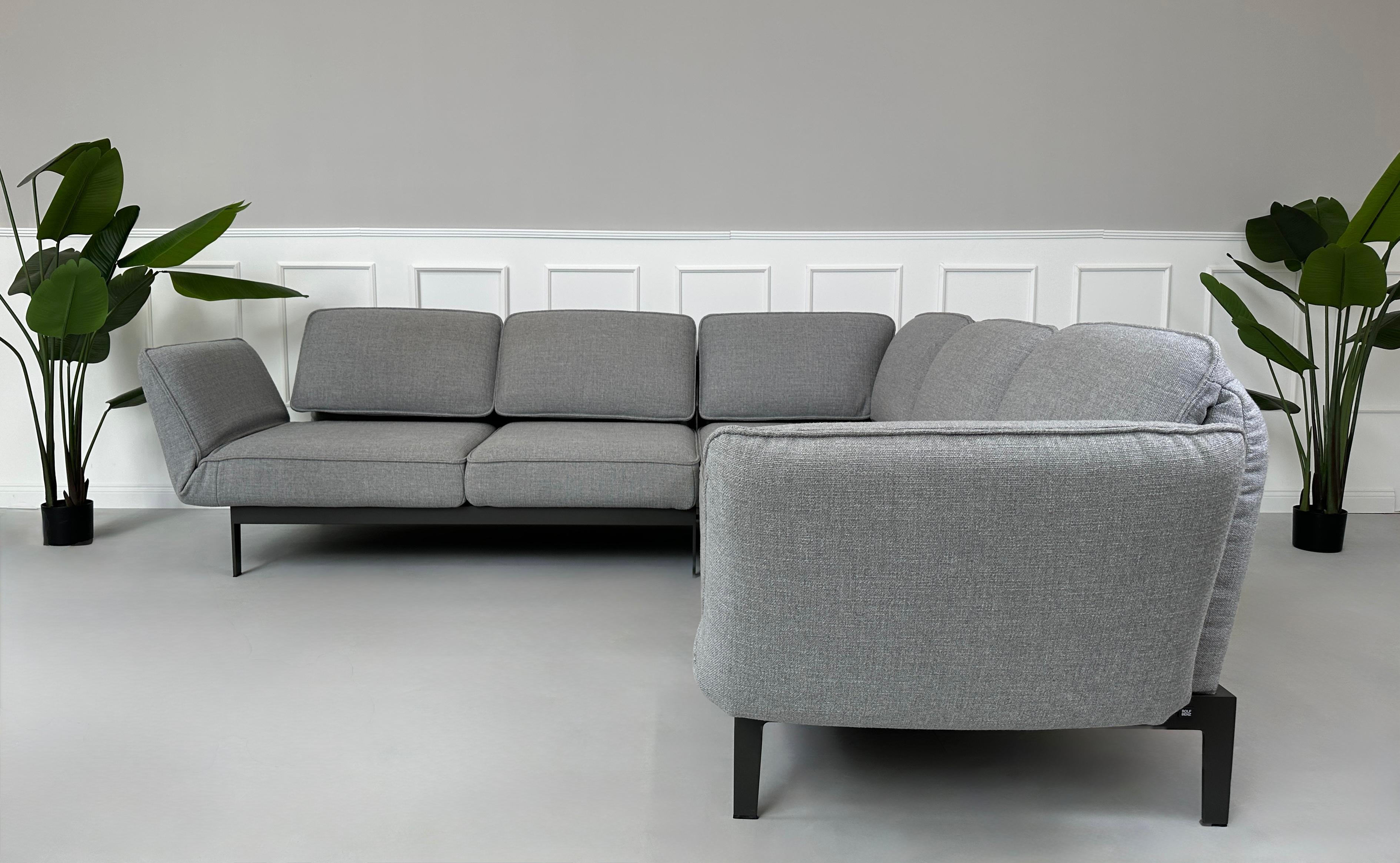 Graues Ausstellungsstück Rolf Benz Mera Designer Stoff Sofa vor einer Wand, stilvoll und modern eingerichtet.