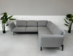 Graues Ausstellungsstück Rolf Benz Mera Designer Stoff Sofa vor einer Wand, stilvoll und modern eingerichtet.