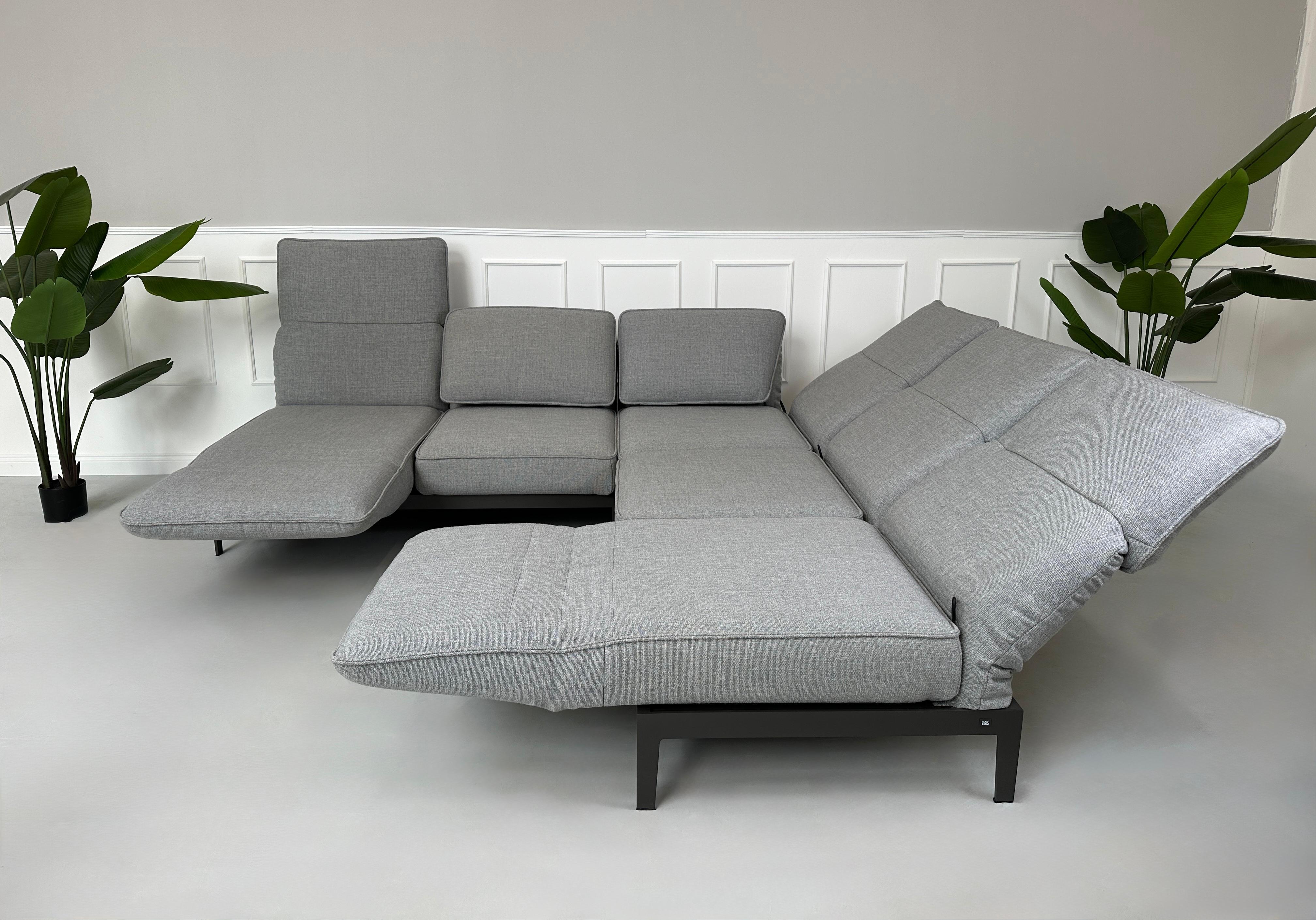 Graues Ausstellungsstück Rolf Benz Mera Designer Stoff Sofa vor einer Wand, stilvoll und modern eingerichtet.