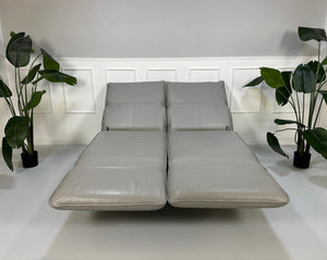 Gebrauchtes graues Rolf Benz Designer Leder Sofa vor einer Wand, stilvoll und modern eingerichtet.