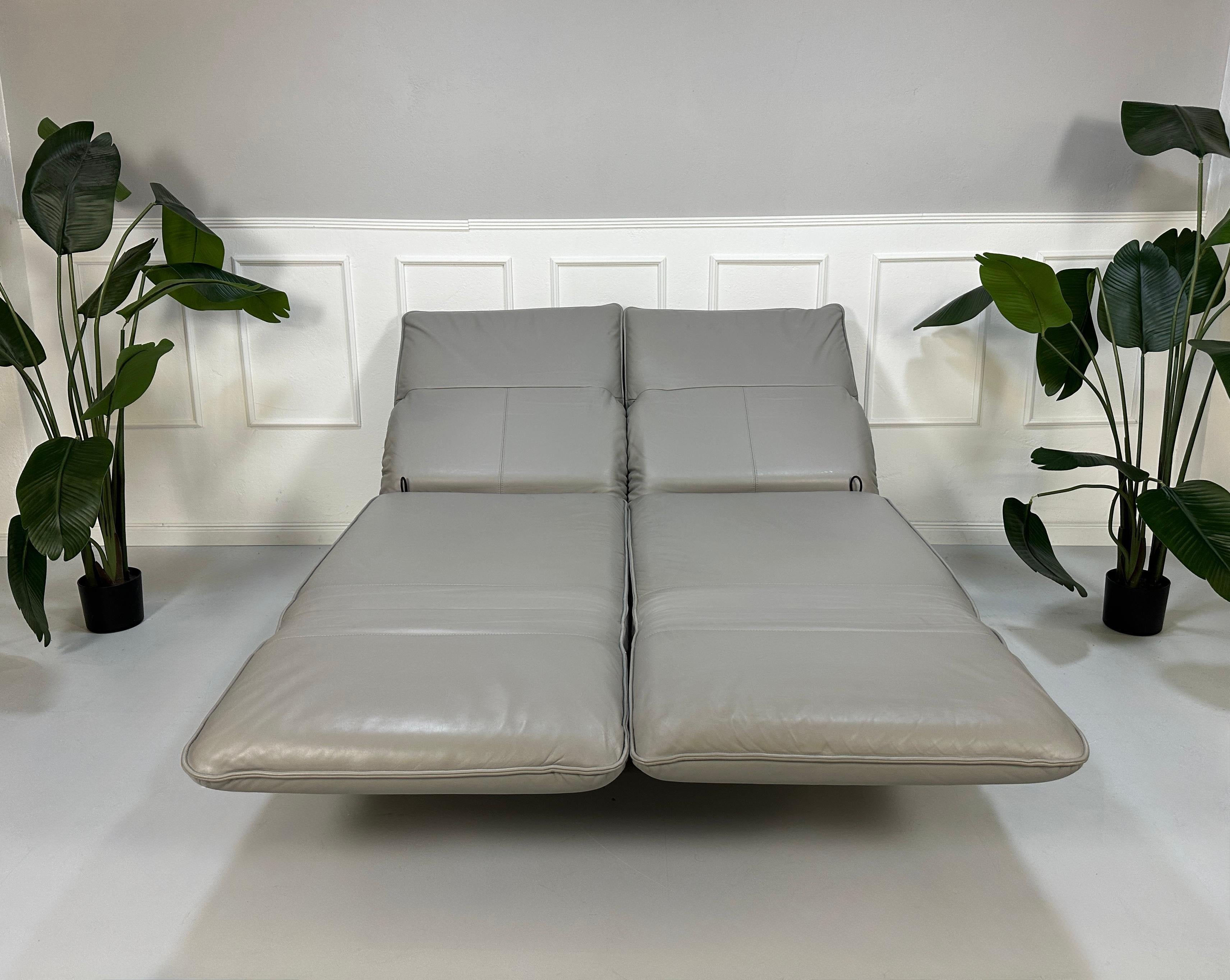 Gebrauchtes graues Rolf Benz Designer Leder Sofa vor einer Wand, stilvoll und modern eingerichtet.