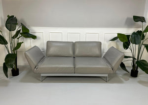 Gebrauchtes graues Rolf Benz Designer Leder Sofa vor einer Wand, stilvoll und modern eingerichtet.