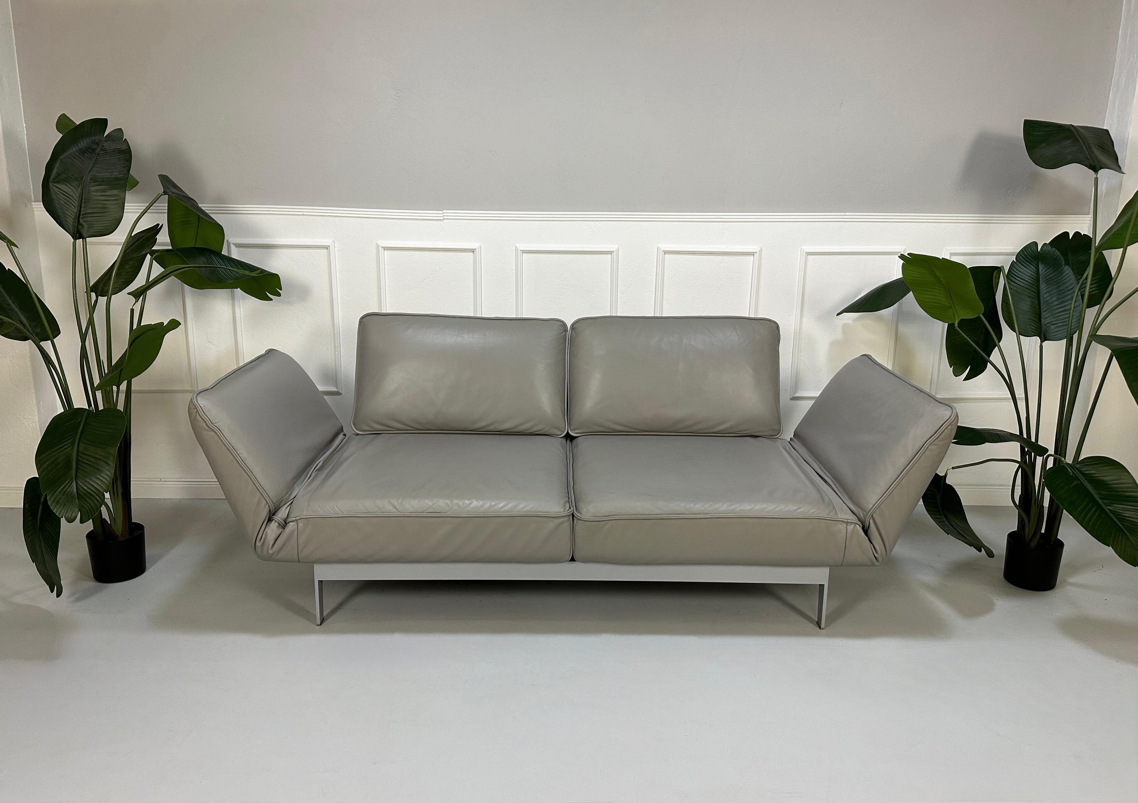 Gebrauchtes graues Rolf Benz Designer Leder Sofa vor einer Wand, stilvoll und modern eingerichtet.