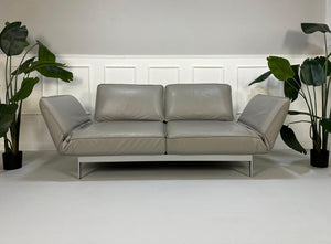 Gebrauchtes graues Rolf Benz Designer Leder Sofa vor einer Wand, stilvoll und modern eingerichtet.