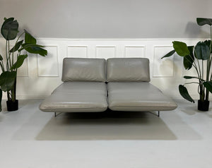 Gebrauchtes graues Rolf Benz Designer Leder Sofa vor einer Wand, stilvoll und modern eingerichtet.