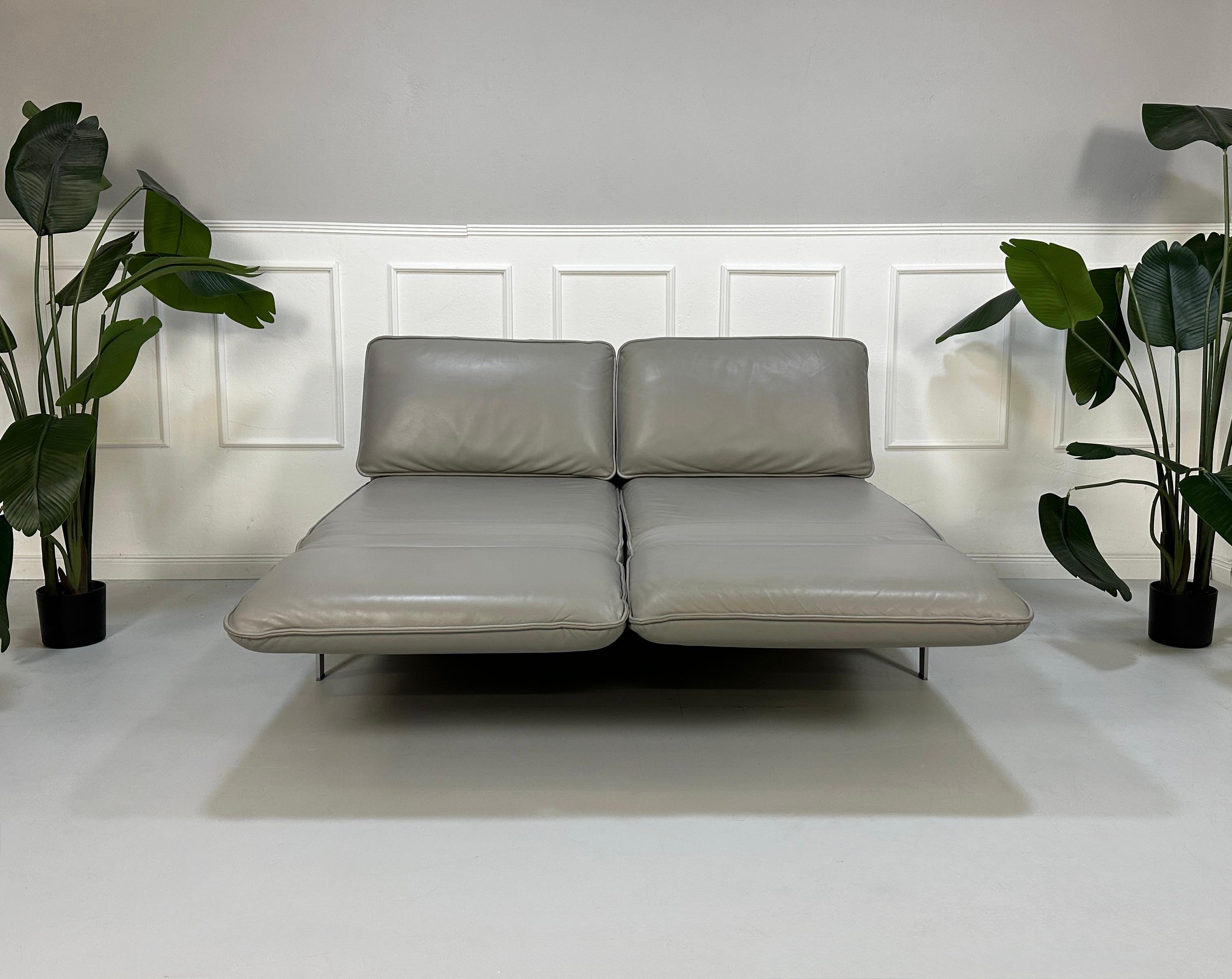 Gebrauchtes graues Rolf Benz Designer Leder Sofa vor einer Wand, stilvoll und modern eingerichtet.
