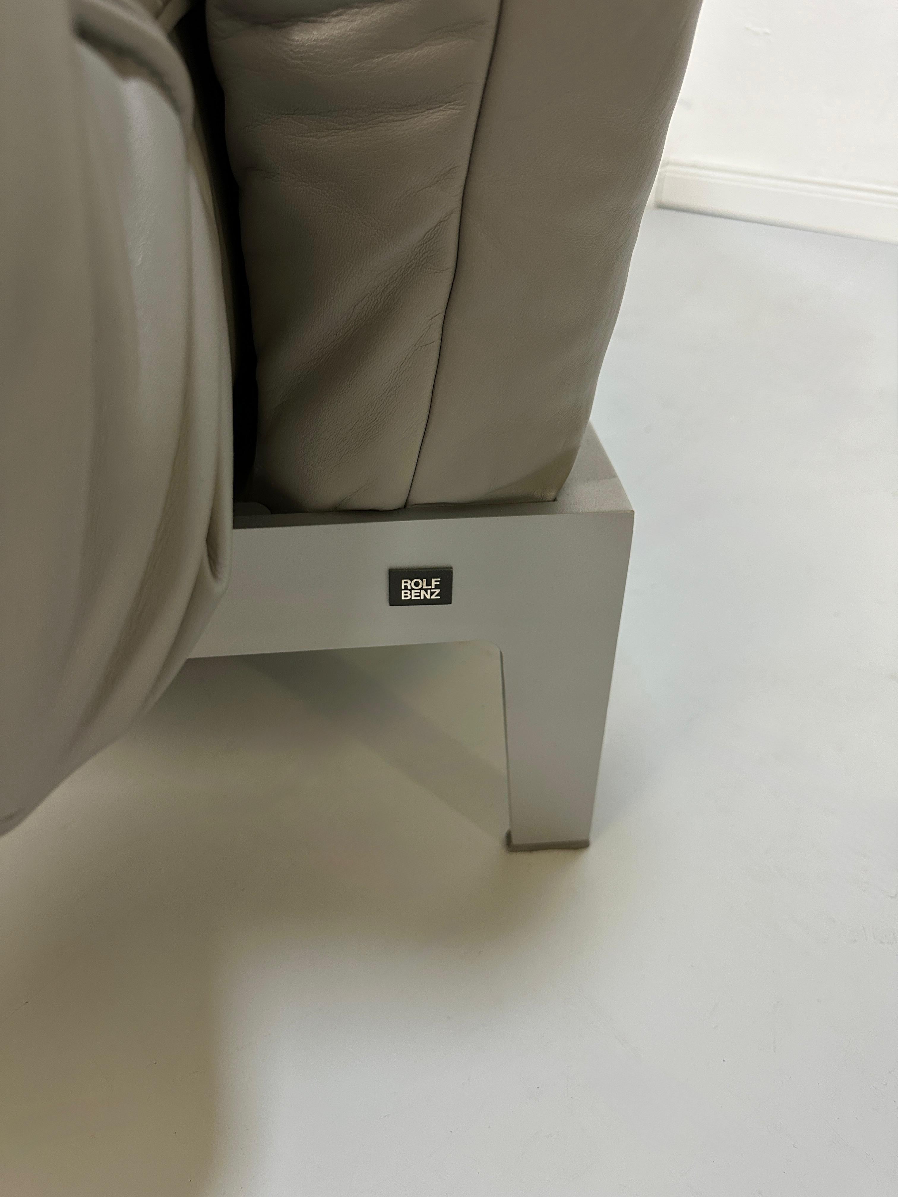 Gebrauchtes graues Rolf Benz Designer Leder Sofa vor einer Wand, stilvoll und modern eingerichtet.