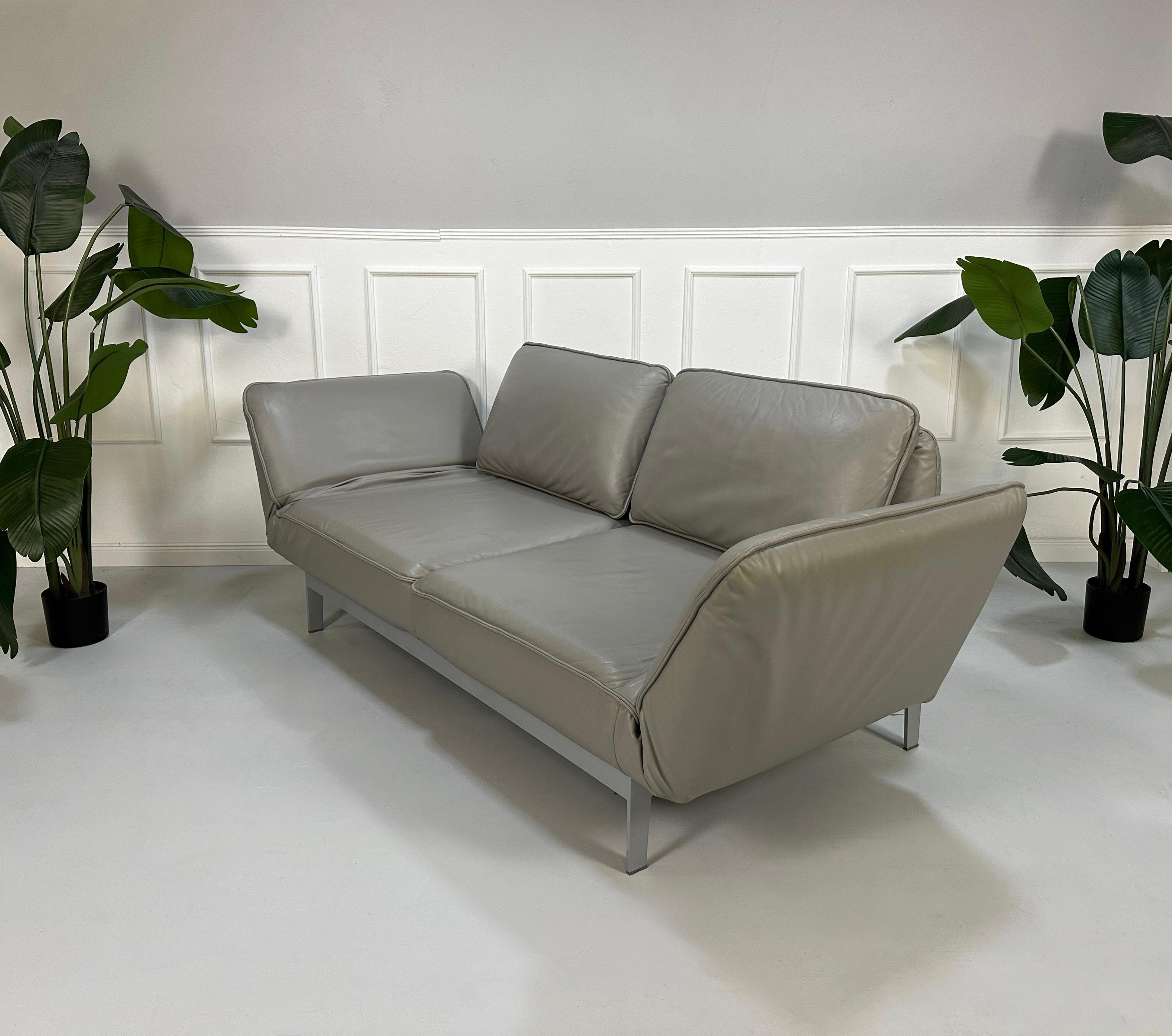 Gebrauchtes graues Rolf Benz Designer Leder Sofa vor einer Wand, stilvoll und modern eingerichtet.