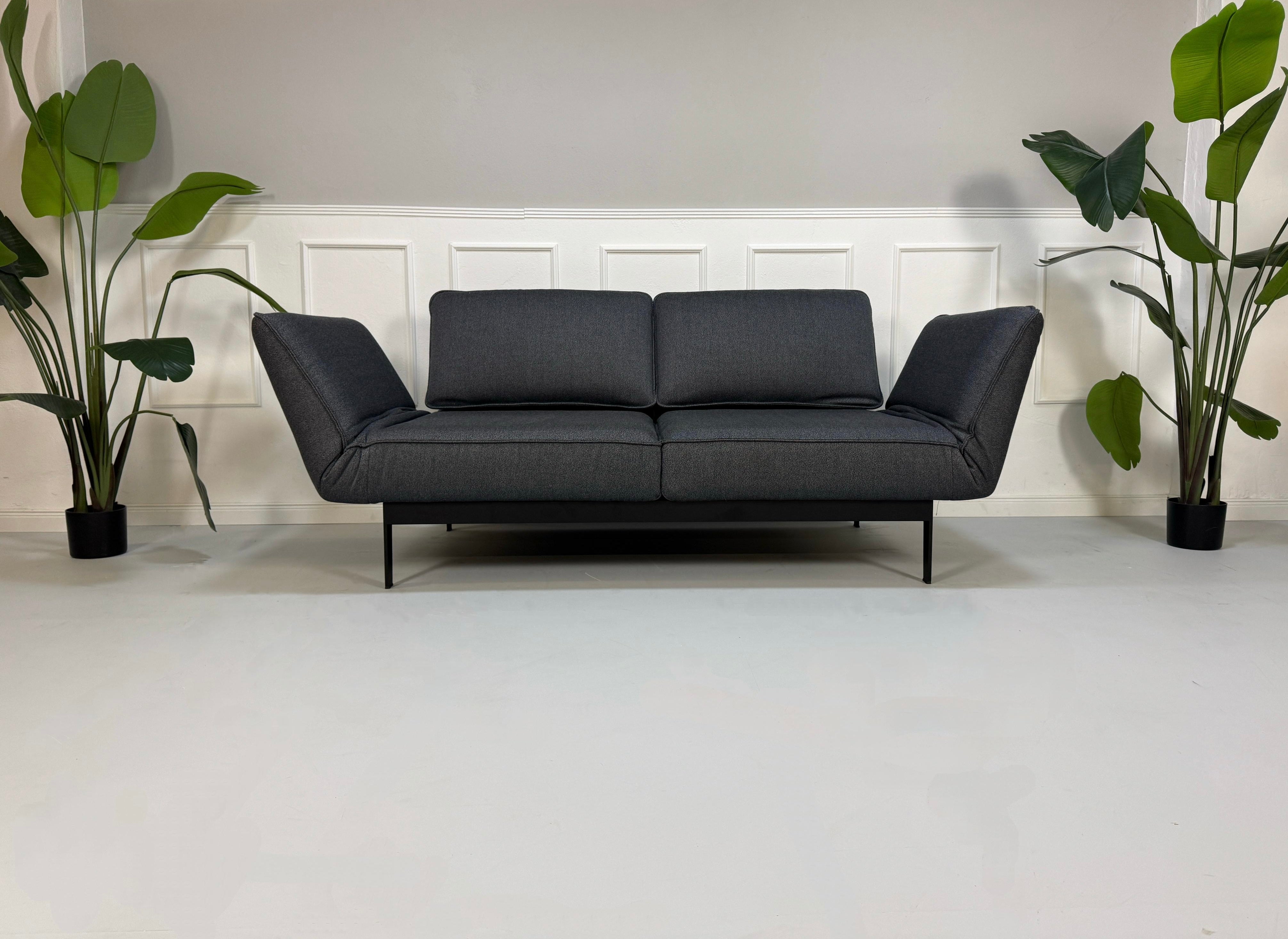 Gebrauchtes graues Rolf Benz Mera Designer Stoff Sofa vor einer Wand, stilvoll und modern eingerichtet.