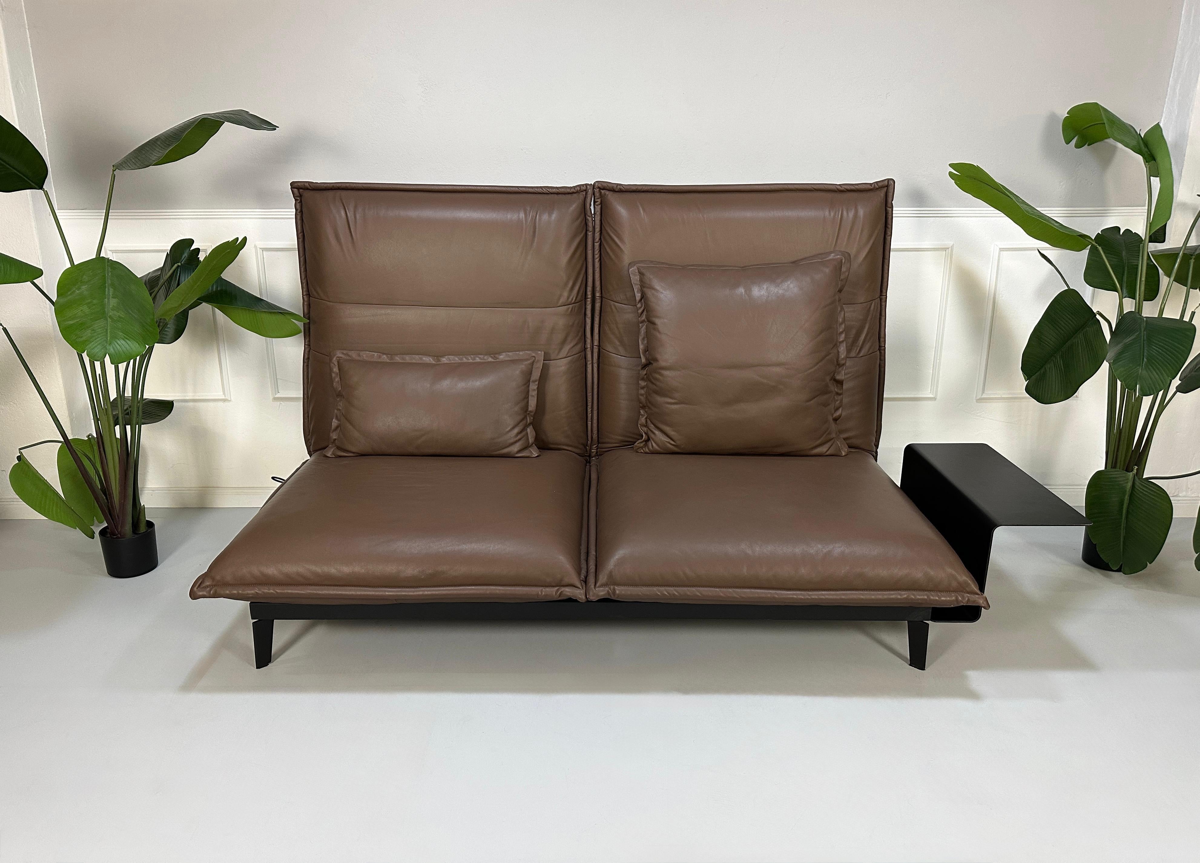 Gebrauchtes braunes Rolf Benz Nova Designer Leder Sofa vor einer Wand, stilvoll und modern eingerichtet.