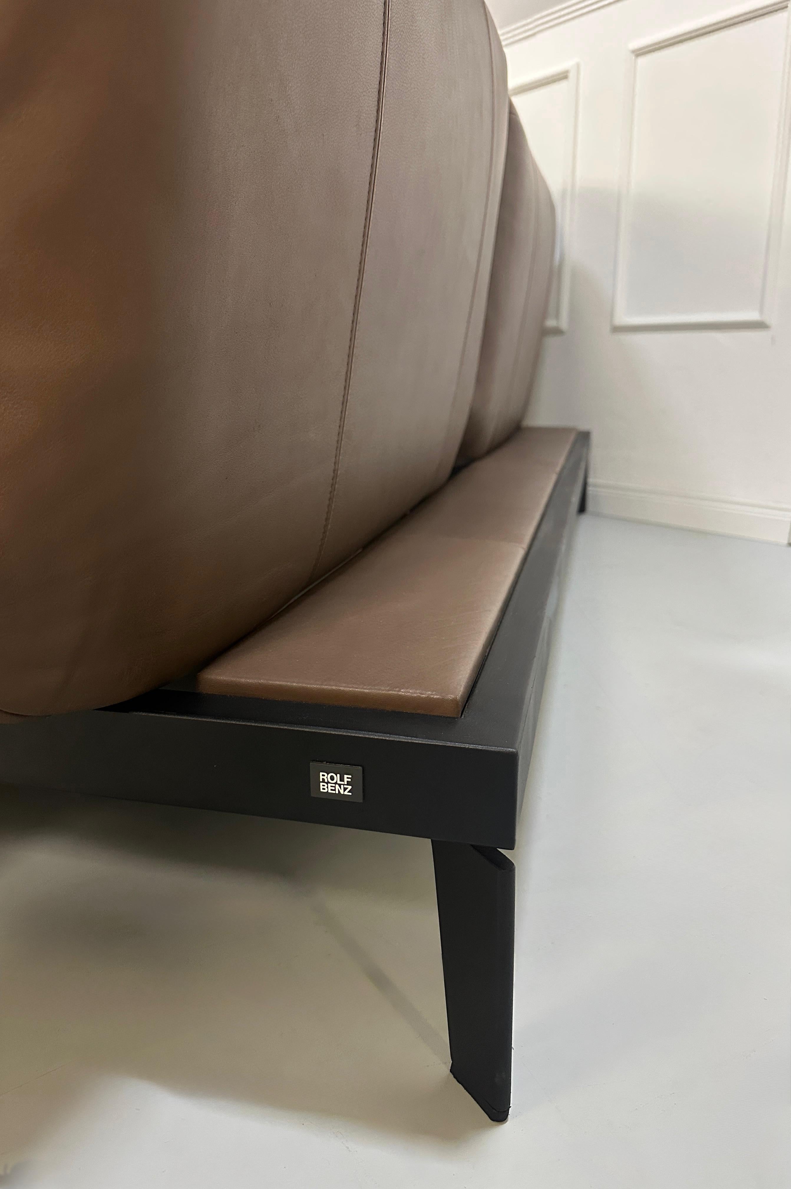 Gebrauchtes braunes Rolf Benz Nova Designer Leder Sofa vor einer Wand, stilvoll und modern eingerichtet.