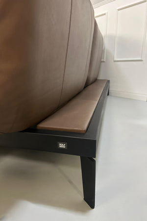 Gebrauchtes braunes Rolf Benz Nova Designer Leder Sofa vor einer Wand, stilvoll und modern eingerichtet.