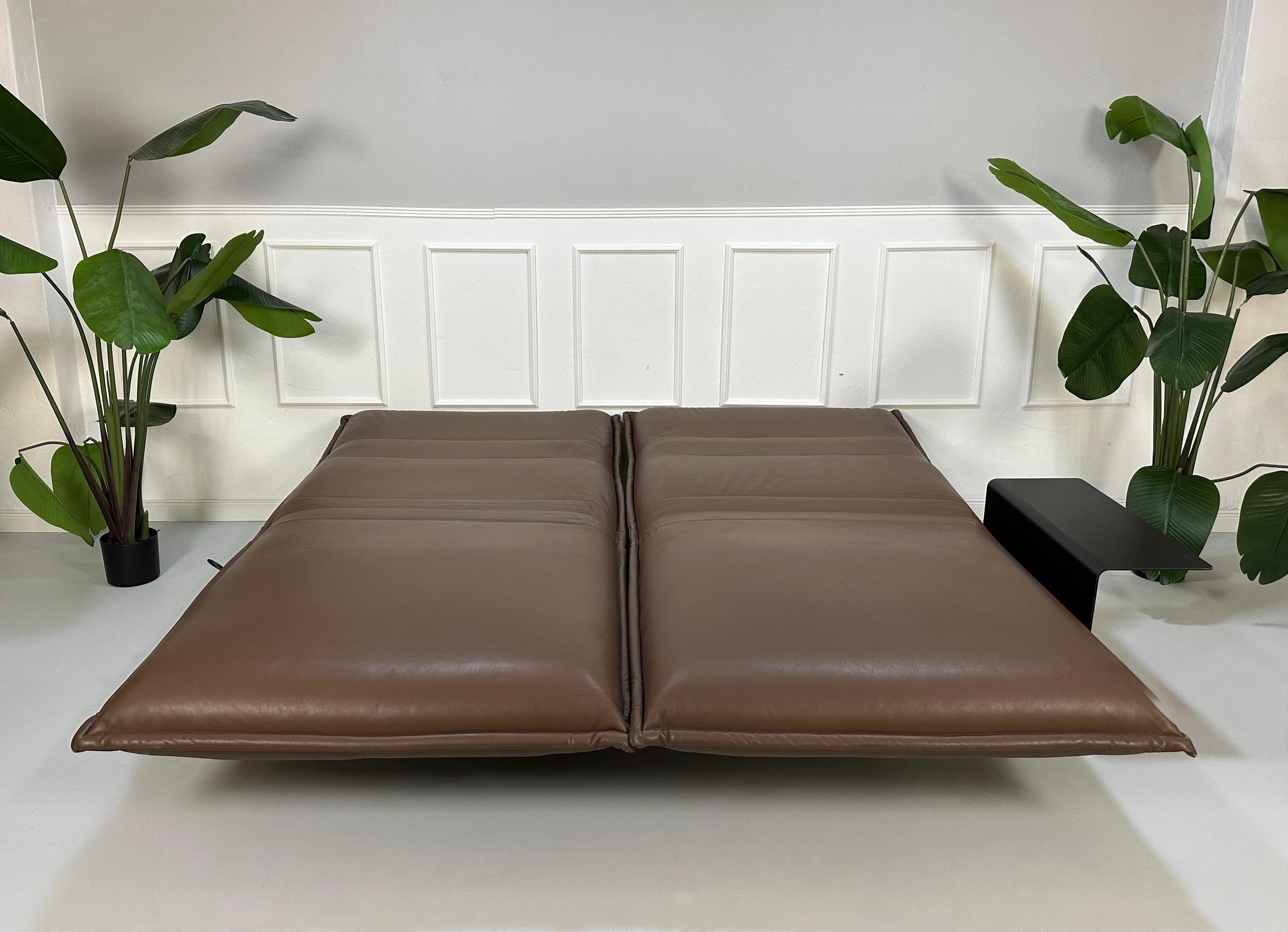 Gebrauchtes braunes Rolf Benz Nova Designer Leder Sofa vor einer Wand, stilvoll und modern eingerichtet.