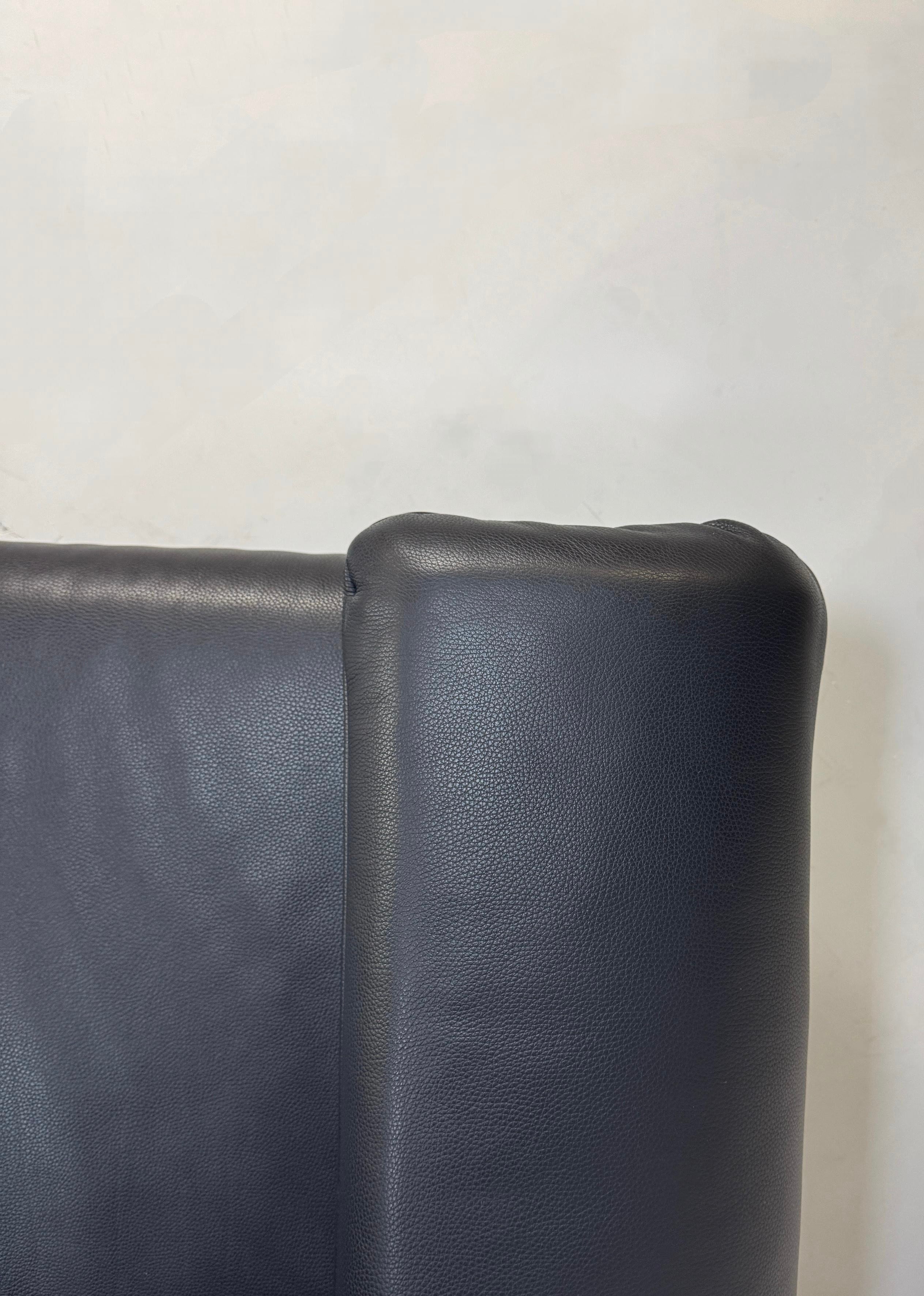 Gebrauchtes Rolf Benz Plura Sofa Leder in der Farbe Blau vor einer Wand, stilvoll und modern eingerichtet.