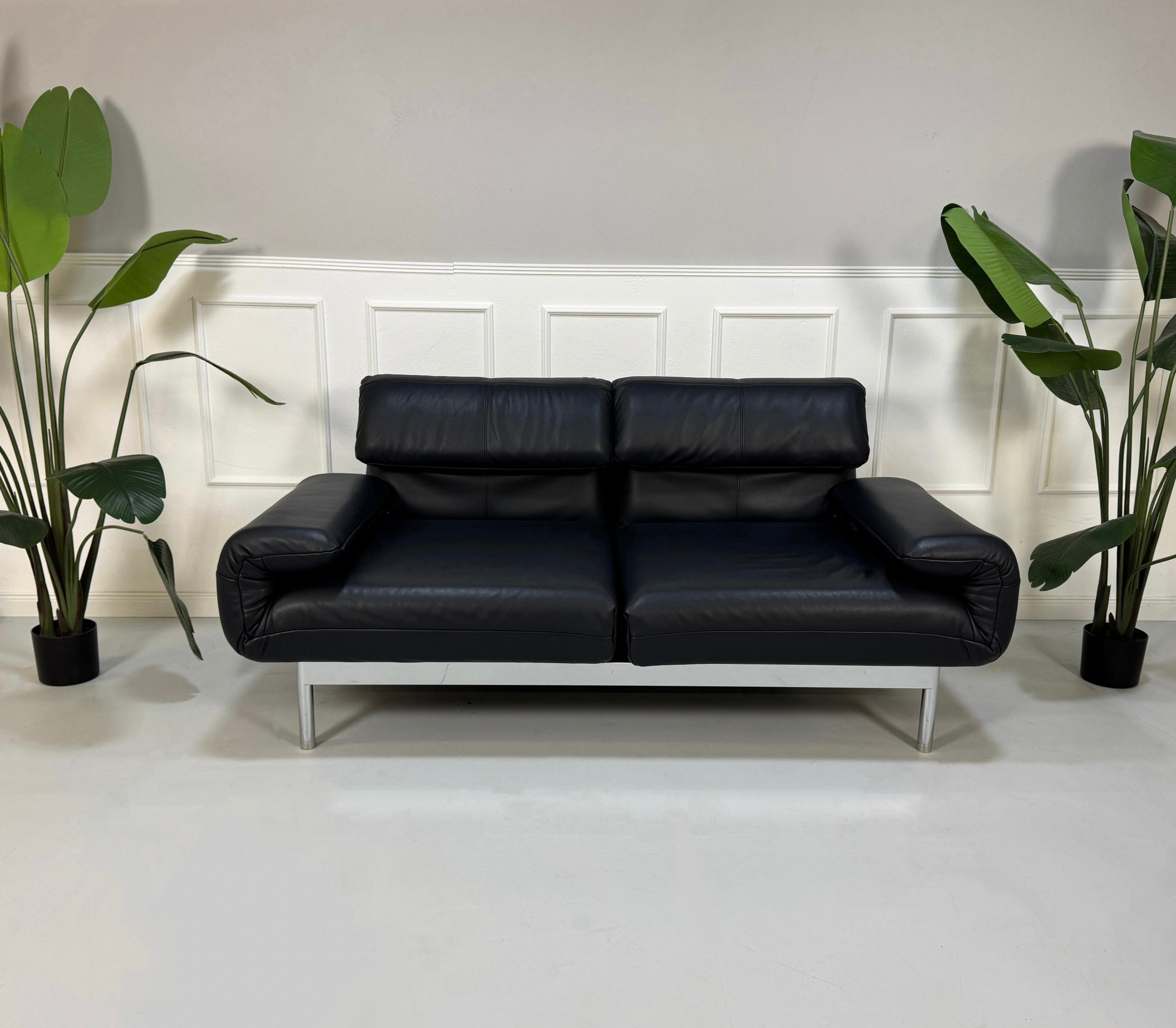 Gebrauchtes Rolf Benz Plura Sofa Leder in der Farbe Blau vor einer Wand, stilvoll und modern eingerichtet.