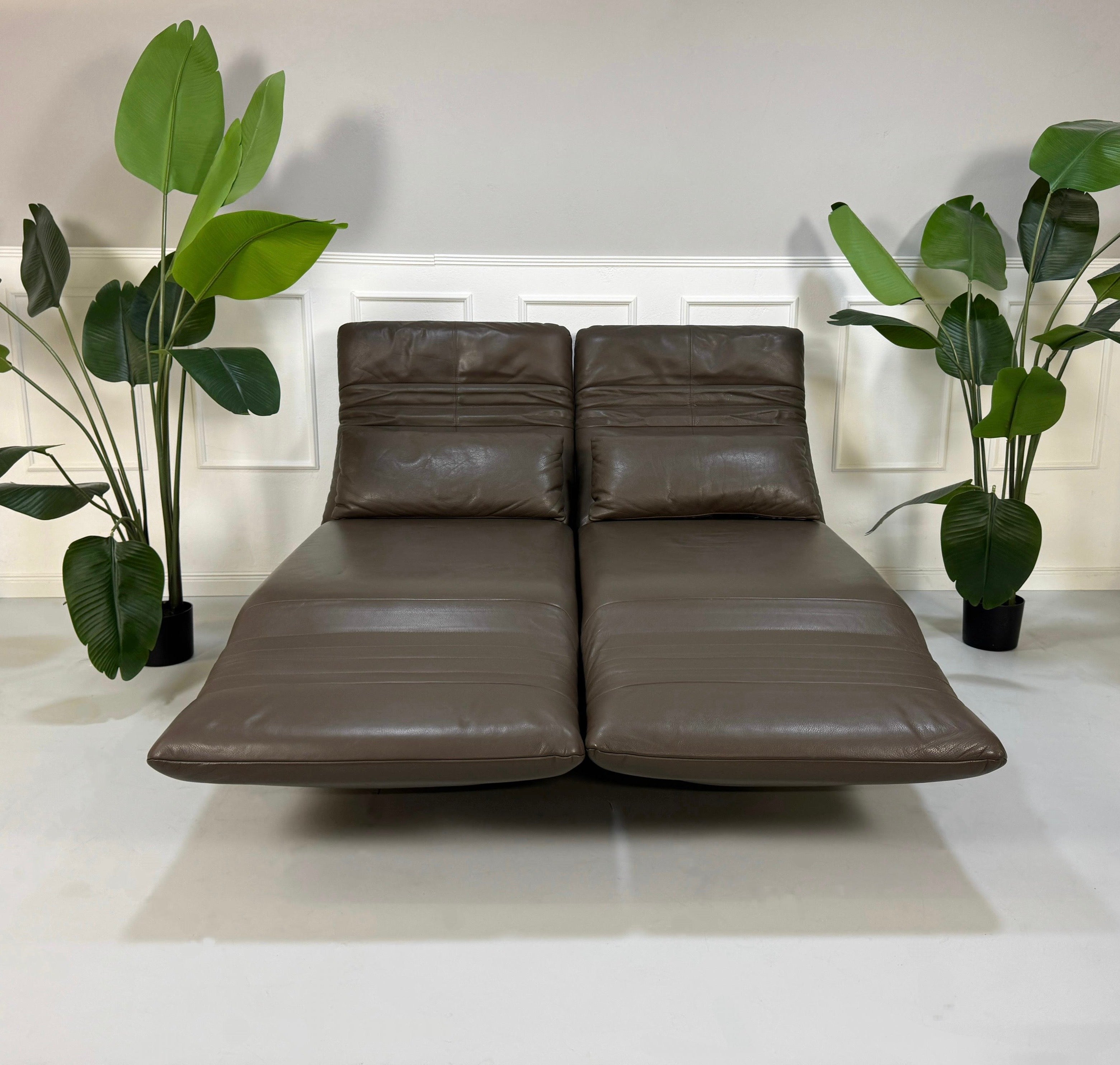 Gebrauchtes Rolf Benz Plura Sofa Leder in der Farbe Braun vor einer Wand, stilvoll und modern eingerichtet.