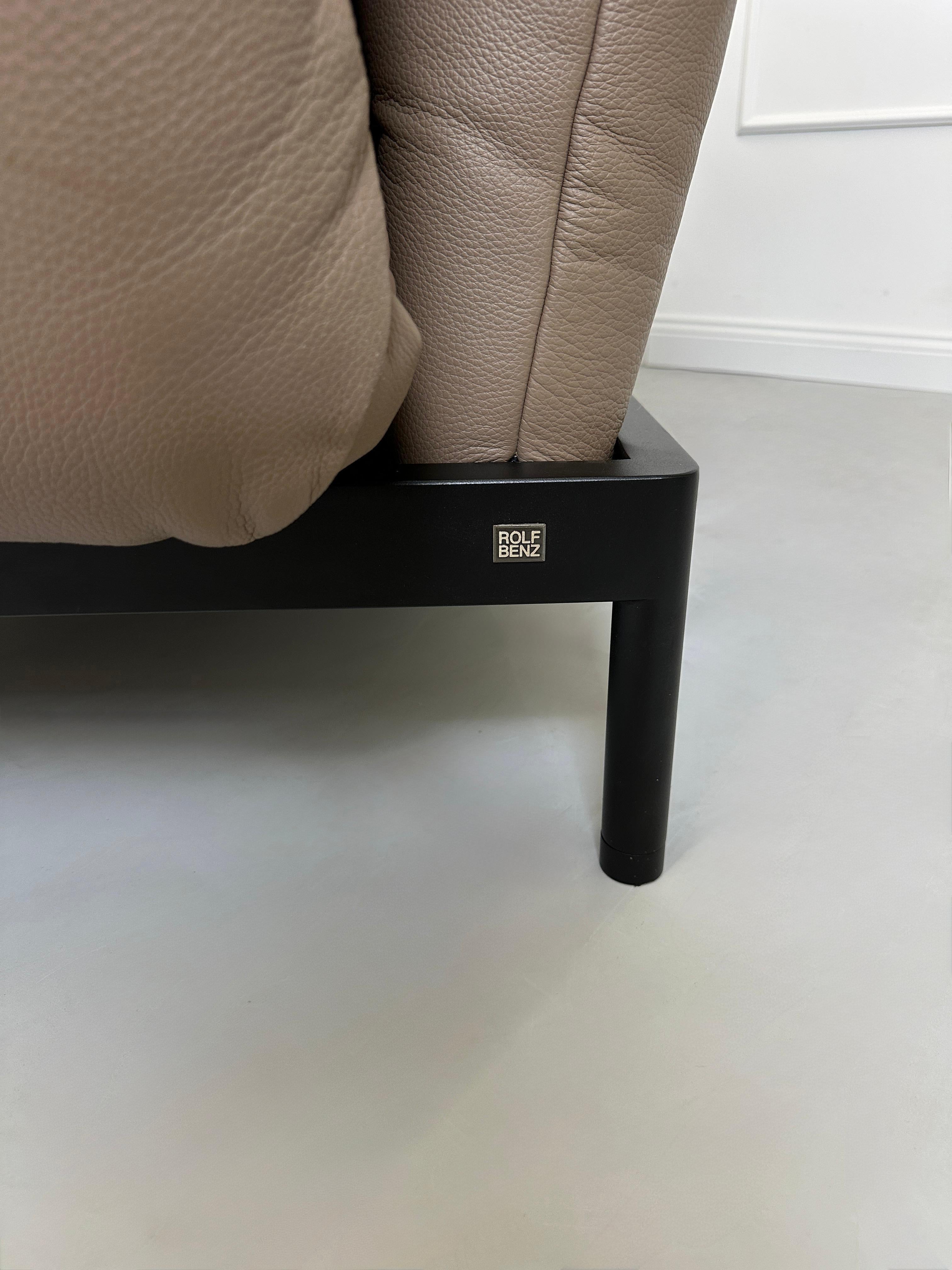 Gebrauchtes braunes Rolf Benz Plura Designer Leder Sofa mit Hocker vor einer Wand, stilvoll und modern eingerichtet.