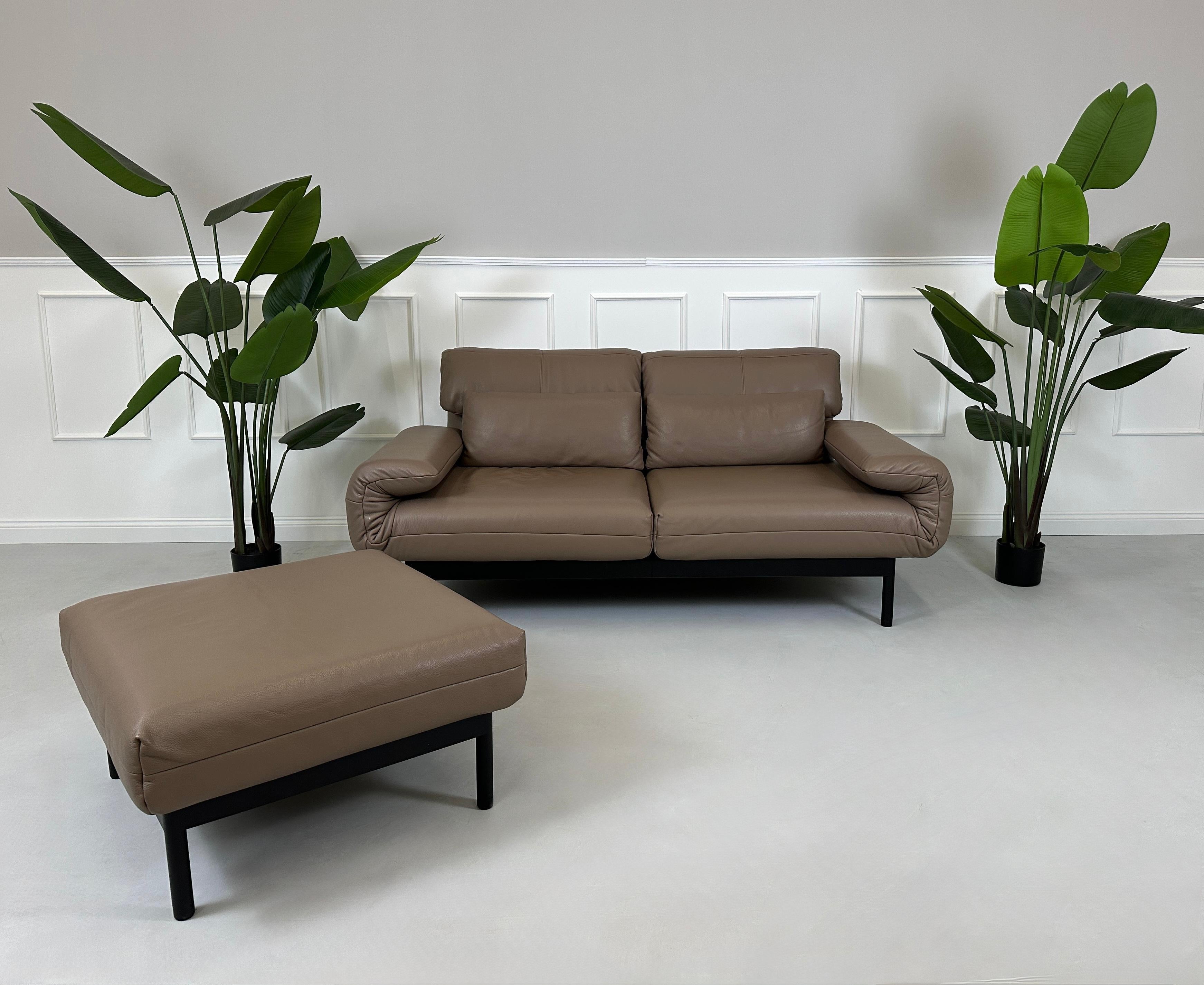Gebrauchtes braunes Rolf Benz Plura Designer Leder Sofa mit Hocker vor einer Wand, stilvoll und modern eingerichtet.