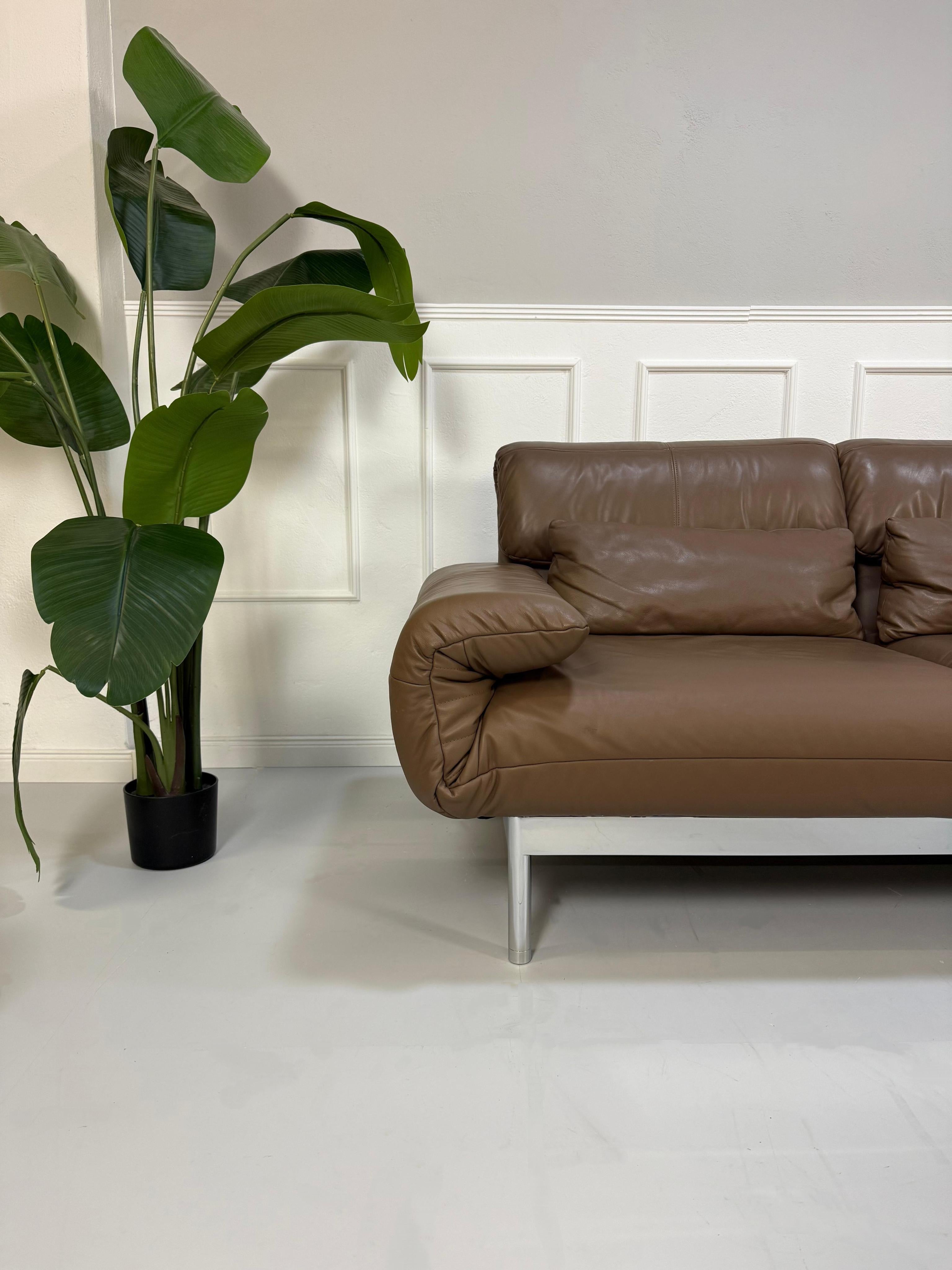 Gebrauchtes braunes Rolf Benz Plura Designer Leder Sofa mit Chromfüßen vor einer Wand, stilvoll und modern eingerichtet.