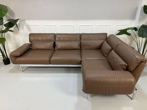 Gebrauchtes braunes Rolf Benz Plura Designer Leder Sofa mit Chromfüßen vor einer Wand, stilvoll und modern eingerichtet.