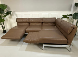Gebrauchtes braunes Rolf Benz Plura Designer Leder Sofa mit Chromfüßen vor einer Wand, stilvoll und modern eingerichtet.