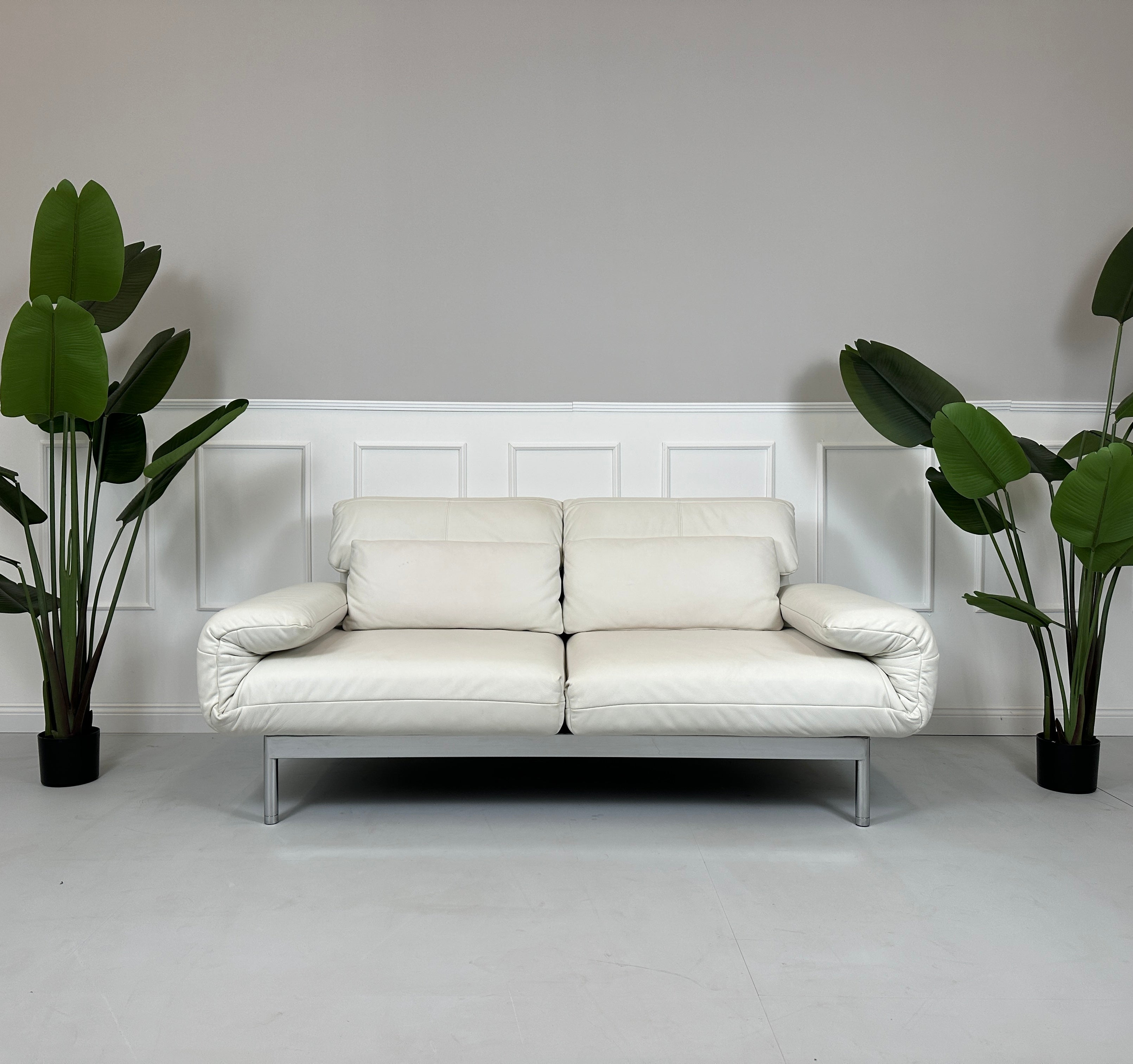 Gebrauchtes weißes Rolf Benz Plura Designer Leder Sofa vor einer Wand, stilvoll und modern eingerichtet.