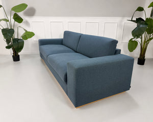 Gebrauchtes blaues Bolia Sepia Designer Stoff Sofa vor einer Wand, stilvoll und modern eingerichtet.