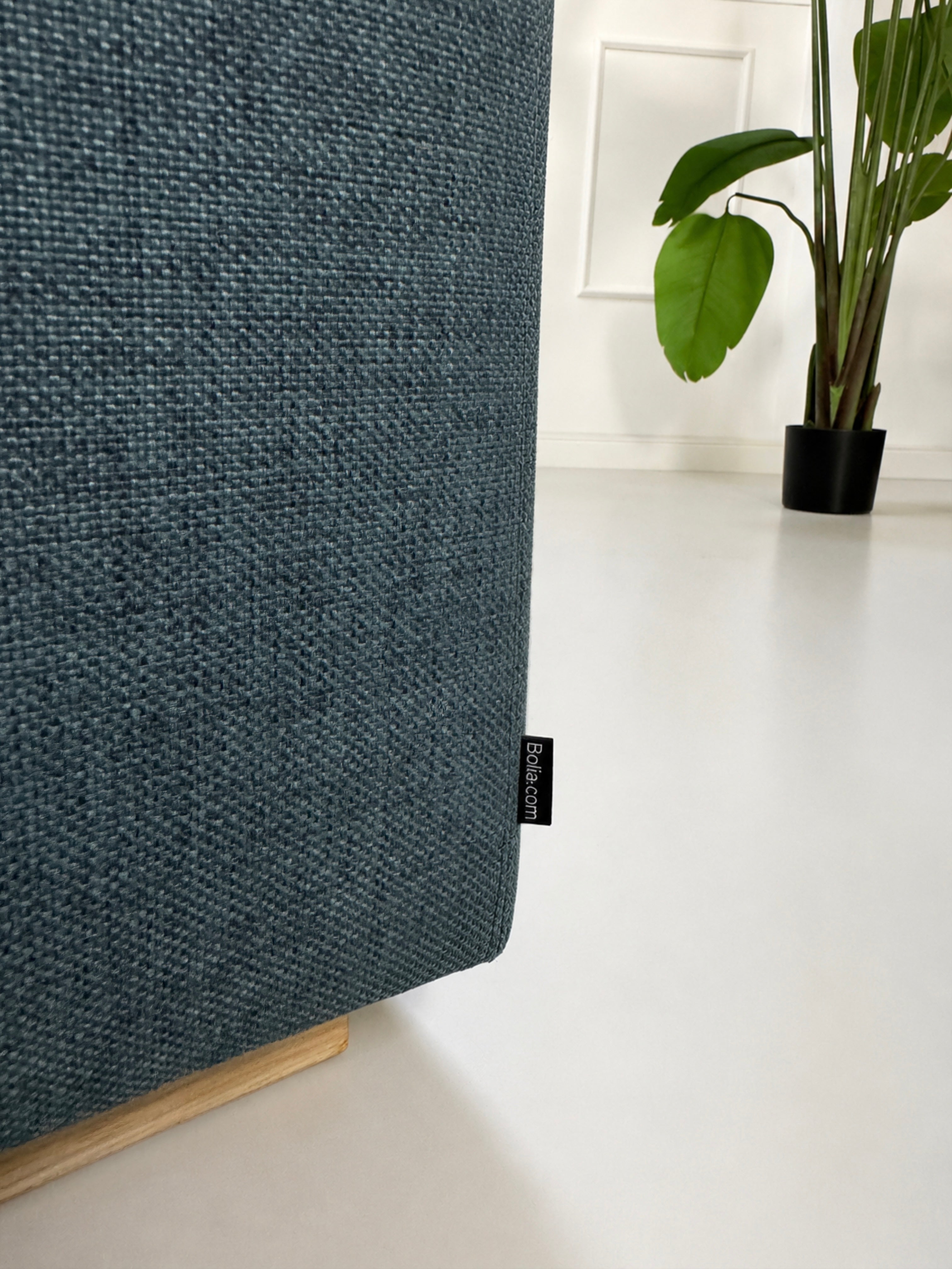 Gebrauchtes blaues Bolia Sepia Designer Stoff Sofa vor einer Wand, stilvoll und modern eingerichtet.