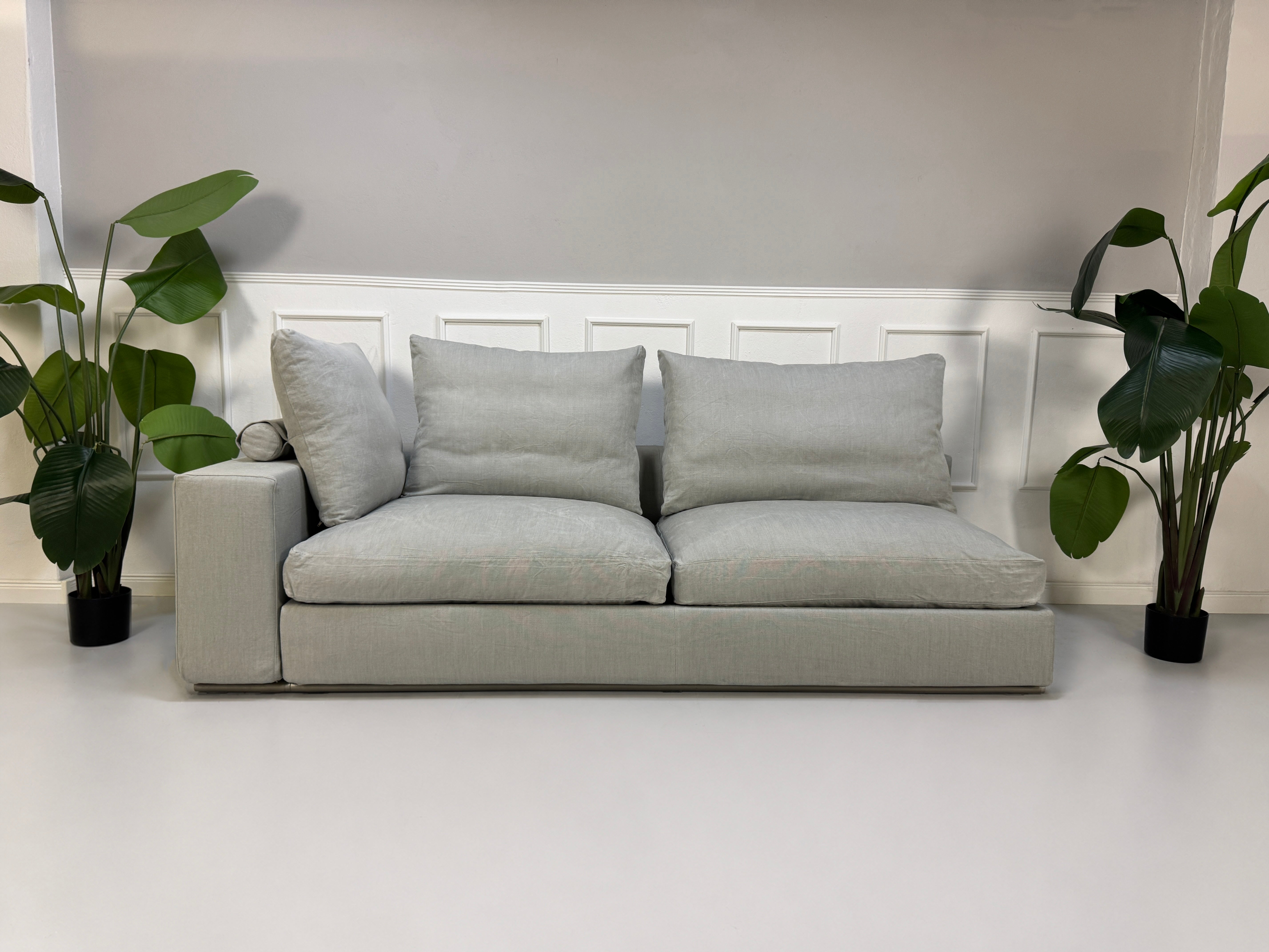 Gebrauchtes graues Flexform Groundpiece Designer Stoff Sofa vor einer Wand, stilvoll und modern eingerichtet.