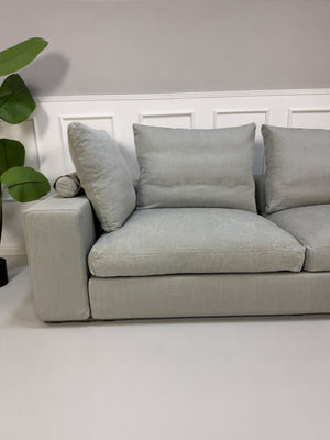 Gebrauchtes graues Flexform Groundpiece Designer Stoff Sofa vor einer Wand, stilvoll und modern eingerichtet.