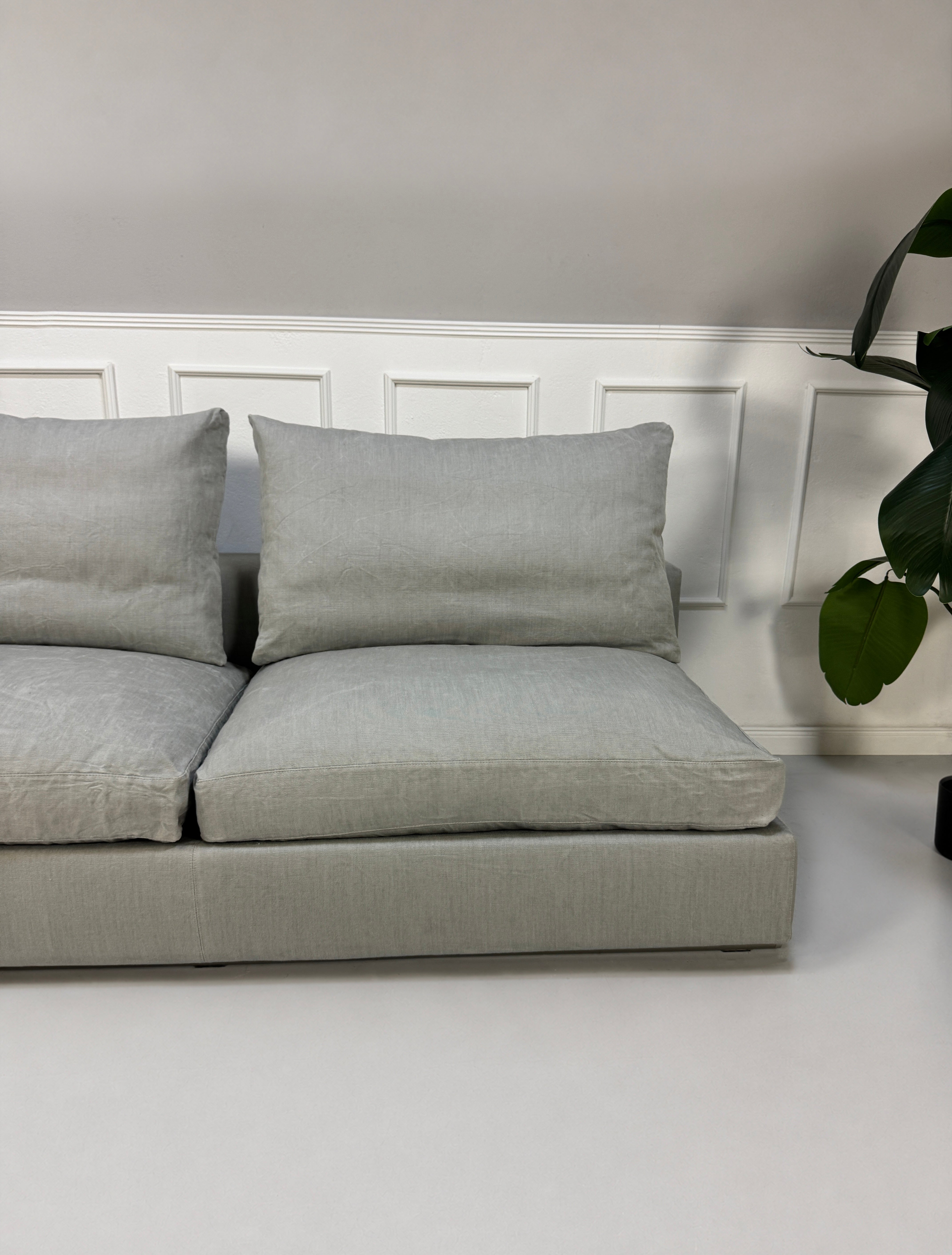 Gebrauchtes graues Flexform Groundpiece Designer Stoff Sofa vor einer Wand, stilvoll und modern eingerichtet.