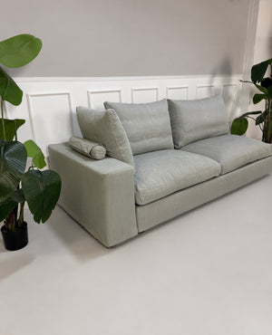 Gebrauchtes graues Flexform Groundpiece Designer Stoff Sofa vor einer Wand, stilvoll und modern eingerichtet.