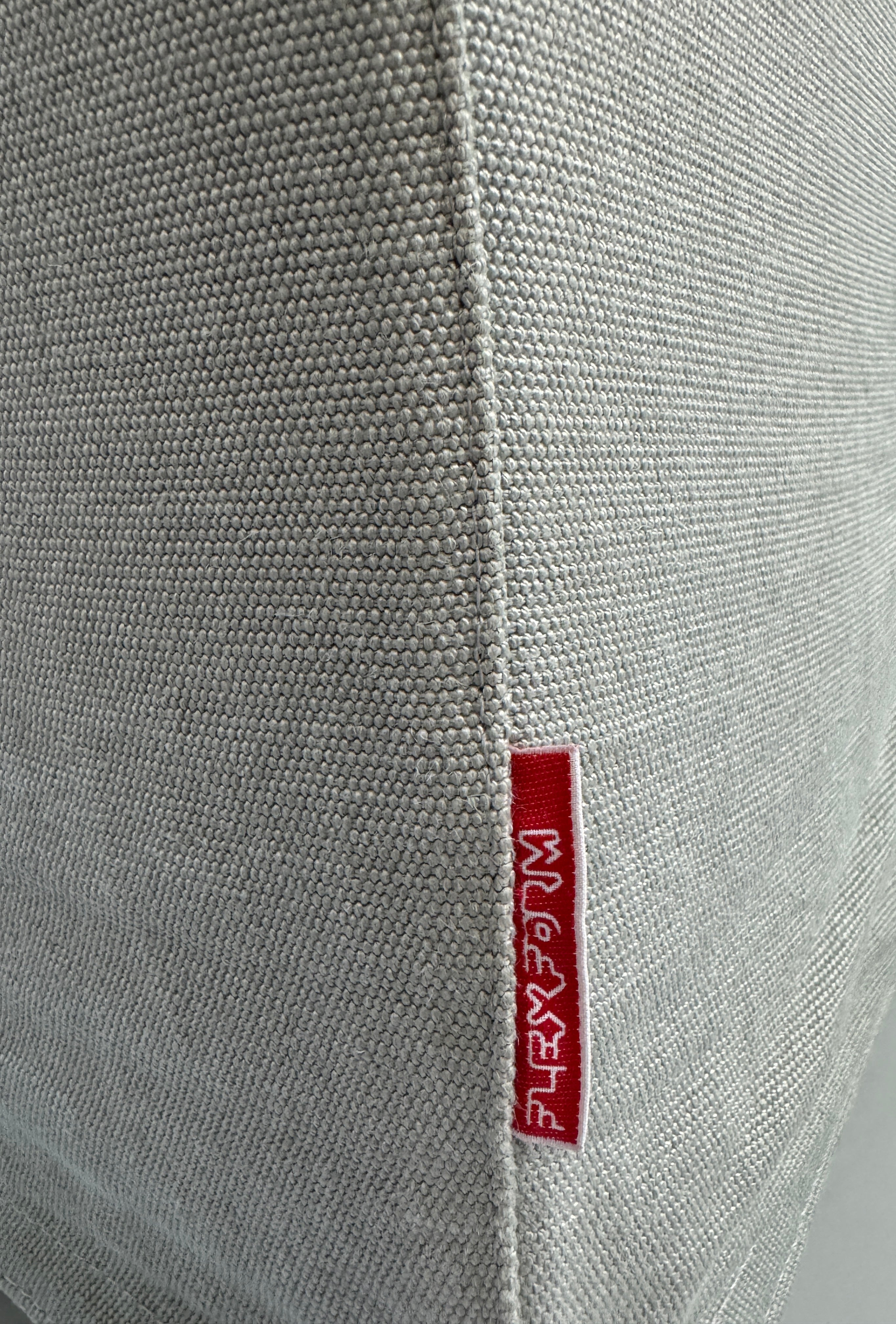 Gebrauchtes graues Flexform Groundpiece Designer Stoff Sofa vor einer Wand, stilvoll und modern eingerichtet.