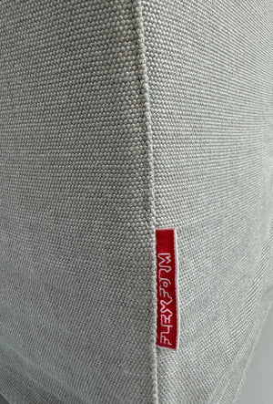 Gebrauchtes graues Flexform Groundpiece Designer Stoff Sofa vor einer Wand, stilvoll und modern eingerichtet.