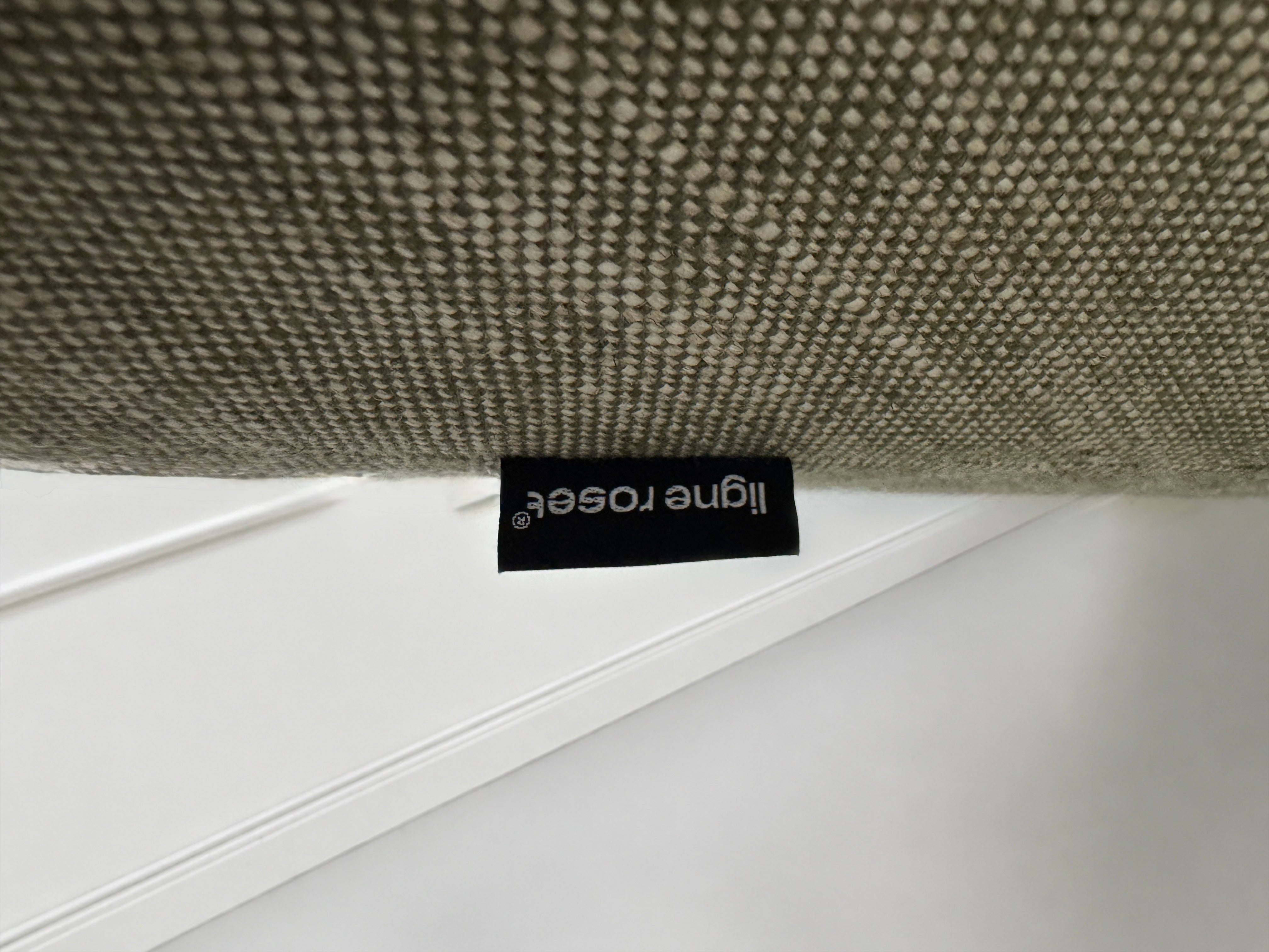 Gebrauchtes graues Ligne Roset Prado Designer Stoff Sofa vor einer Wand, stilvoll und modern eingerichtet.