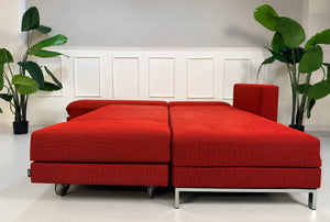 Gebrauchtes rotes Brühl FourTwo Designer Stoff Ecksofa vor einer Wand, stilvoll und modern eingerichtet.