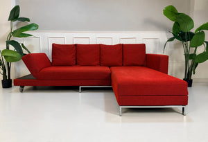Gebrauchtes rotes Brühl FourTwo Designer Stoff Ecksofa vor einer Wand, stilvoll und modern eingerichtet.