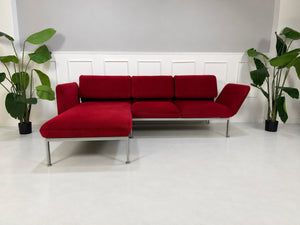 Gebrauchtes rotes Brühl Roro Medium Designer Stoff Ecksofa vor einer Wand, stilvoll und modern eingerichtet.