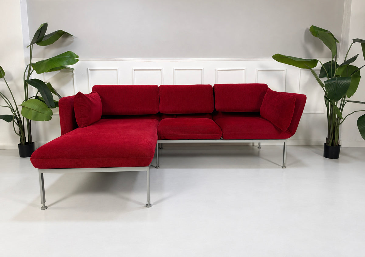 Gebrauchtes rotes Brühl Roro Medium Designer Stoff Ecksofa vor einer Wand, stilvoll und modern eingerichtet.