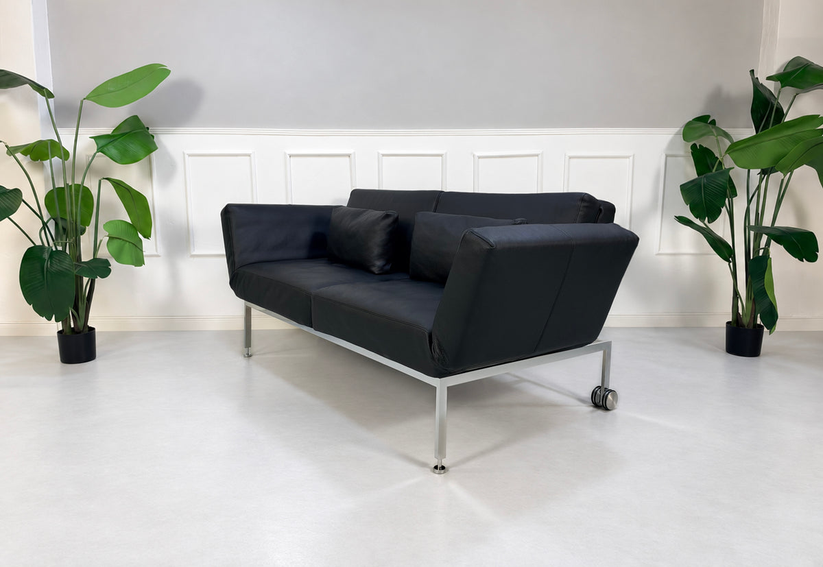 Gebrauchtes schwarzes Brühl Roro Soft Medium Designer Leder Sofa vor einer Wand, stilvoll und modern eingerichtet.