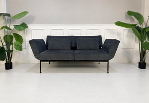 Gebrauchtes graues Brühl Roro Soft Medium Designer Stoff Sofa vor einer Wand, stilvoll und modern eingerichtet.