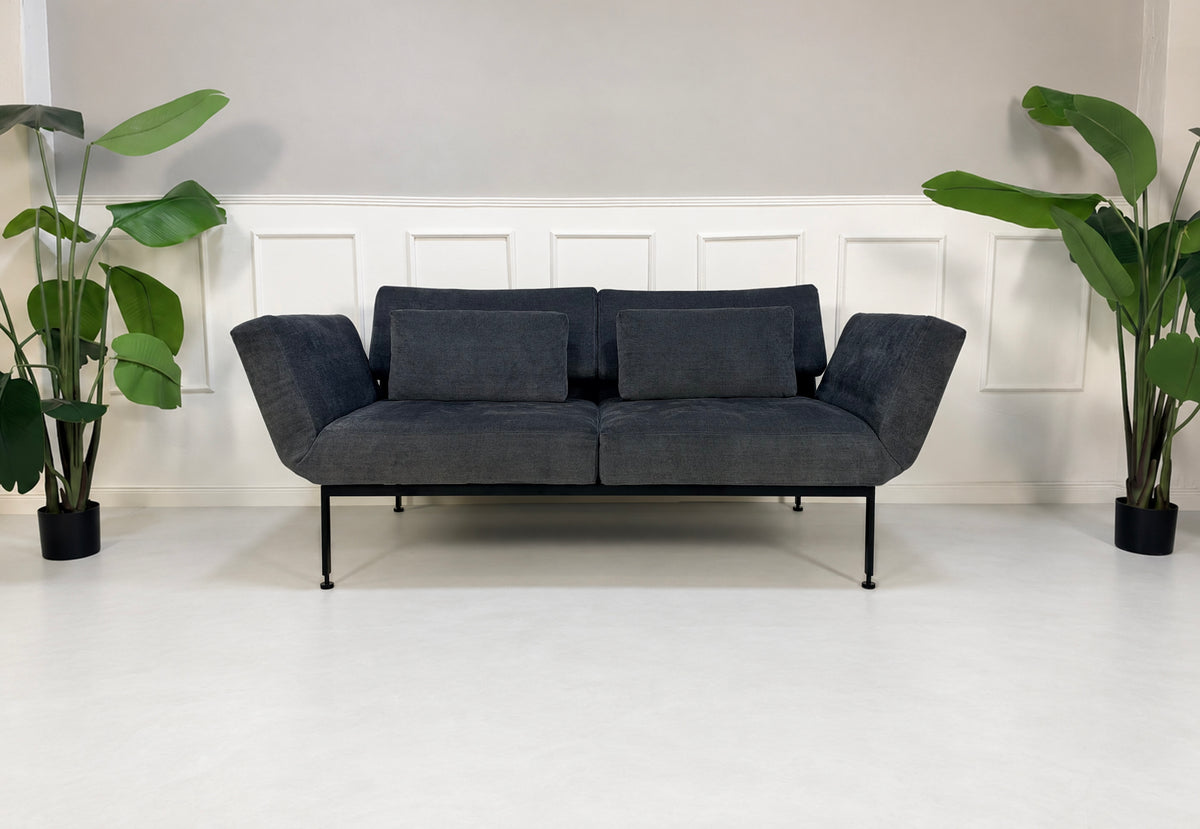 Gebrauchtes graues Brühl Roro Soft Medium Designer Stoff Sofa vor einer Wand, stilvoll und modern eingerichtet.