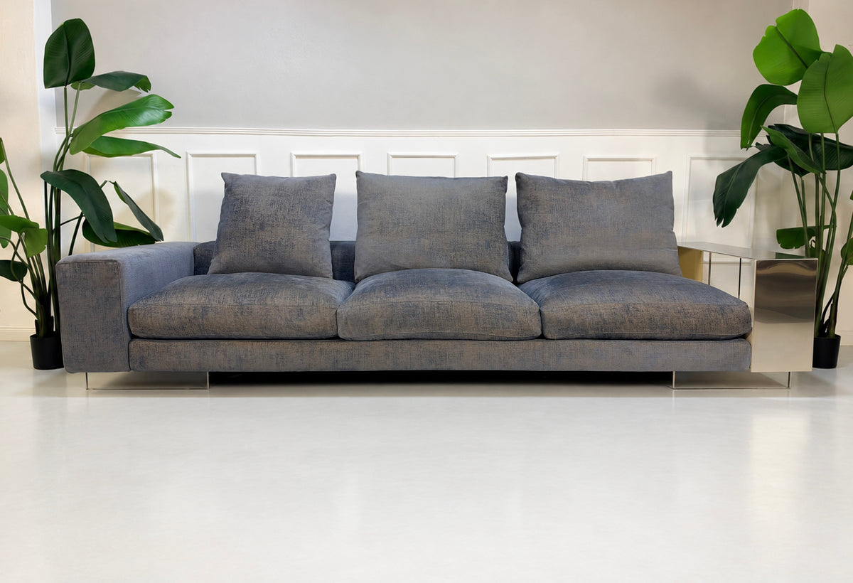 Gebrauchtes grau-blaues Flexform Lightpiece Designer Stoff Sofa vor einer Wand, stilvoll und modern eingerichtet.